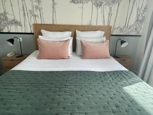 Una cama con dos almohadas rosas encima. en Hôtel Le Martray, en Ars-en-Ré