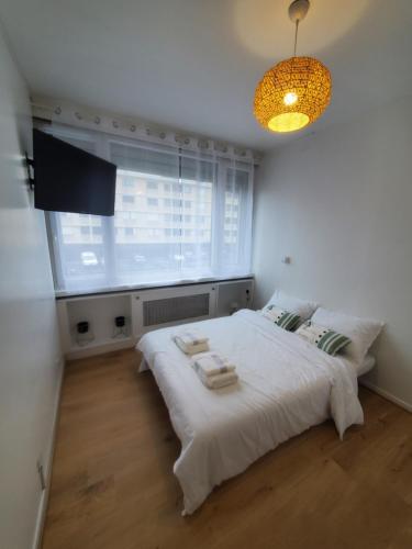 a bedroom with a white bed and a window at Apartment 2 or 3 bedrooms near Paris in Suresnes