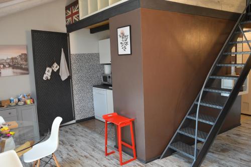 uma cama alta numa cozinha com um banco vermelho em La petite maison de Claire em Cuneo