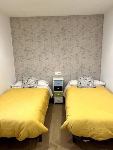 two beds in a room with yellow beds at ANGELFLAT CENTRO in Ronda