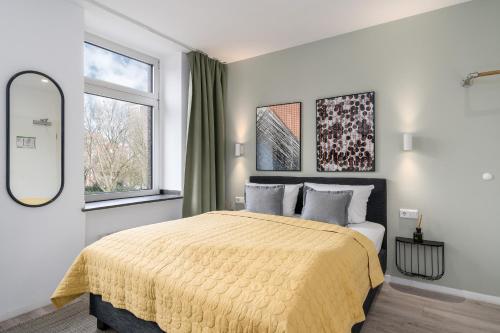 een slaapkamer met een groot bed en een gele deken bij BRIGHT Dortmund City Center in Dortmund