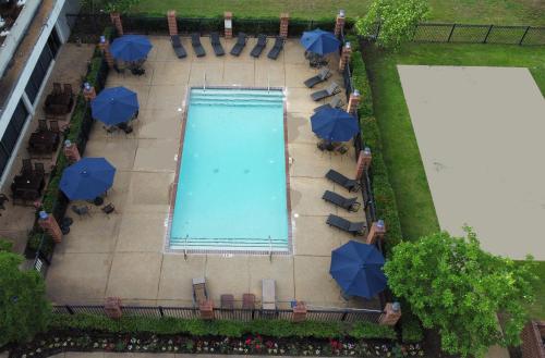 een uitzicht over een zwembad met blauwe parasols bij Historic Whispering Woods Hotel & Conference Center in Olive Branch