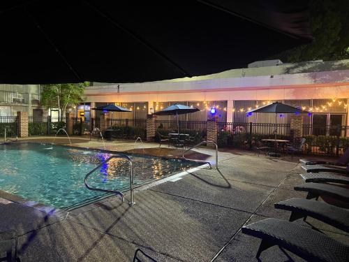 a swimming pool with chairs and umbrellas in front of a building at Historic Whispering Woods Hotel & Conference Center in Olive Branch
