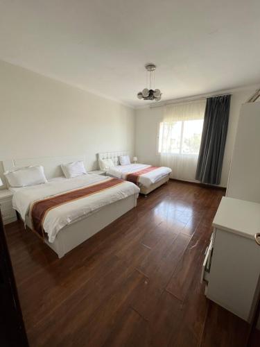 two beds in a room with wooden floors at درة العروس فخامة فان بيتش in Durat  Alarous