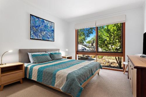 een slaapkamer met een bed en een groot raam bij 1 Gordon St Cowes Kenros Beach House in Cowes