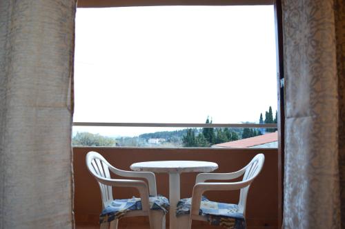 a table and chairs on a balcony with a view at Αndreas Studios in Ipsos