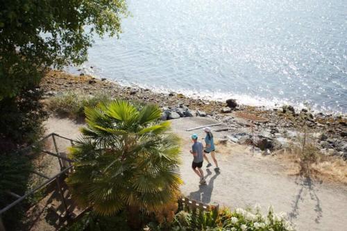 two people walking on the beach near the water at Iconic 3-Story Waterfront 'Marina House' w/ View in Gibsons