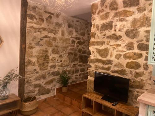 a room with a stone wall with a flat screen tv at Posada de Lola in El Molar