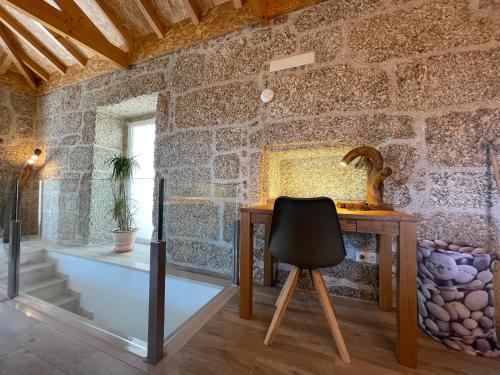 Habitación con paredes de piedra, escritorio y silla. en Casa Botica - Gerês Country House, en Terras de Bouro