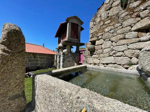 a stone wall with a fountain in front of a building at Casa Botica - Gerês Country House in Terras de Bouro