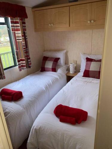two beds in a bedroom with red pillows on them at No29 at Three Lochs Holiday Park in Balminnoch