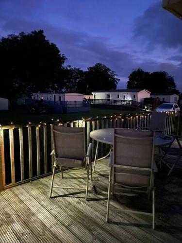 two chairs and a table on a deck at night at No29 at Three Lochs Holiday Park in Balminnoch