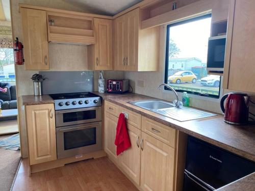 a kitchen with a stove and a sink and a window at No29 at Three Lochs Holiday Park in Balminnoch