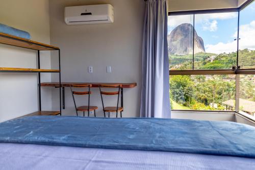 ein Schlafzimmer mit einem Bett und zwei Stühlen vor einem Fenster in der Unterkunft Villaggio Ronchi in Pedra Azul