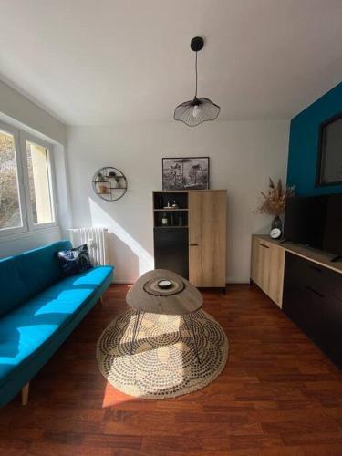 a living room with a blue couch and a table at Cosy F2 Royat Thermes in Royat