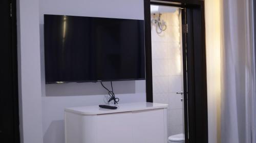 TV de pantalla plana en la parte superior de un armario blanco en Jeffston Court Apartments en Accra