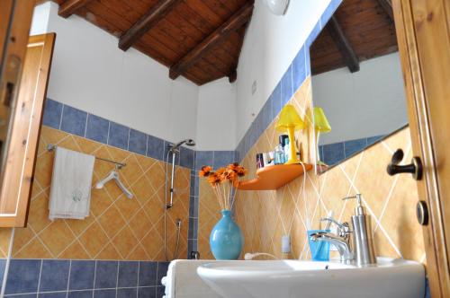 a bathroom with a sink and a vase with flowers in it at B&B CasaCorì in Orosei