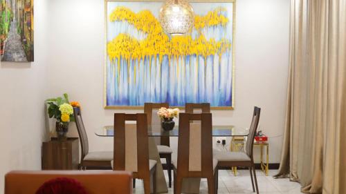 a dining room with a table and chairs and a painting at Luxury 3BR Apartment in Ghana Jeffston Court Accra Prime Location & Comfort in Accra