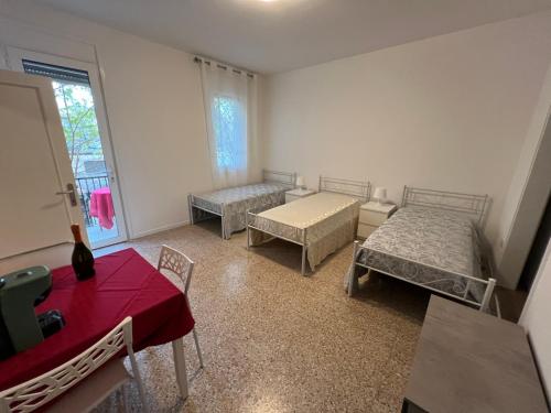 een kamer met 2 bedden en een rode tafel bij Casa Roma rooms& apartmens in Padua