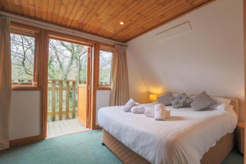 a bedroom with a bed and a large window at Retreat to Oak Tree Lodge - A Romantic Getaway in Devon's Finlake Resort & Spa in Chudleigh