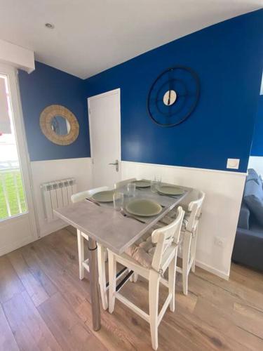 een eettafel met stoelen en een blauwe muur bij Appartement bord de mer in Wimereux