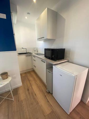 a kitchen with white cabinets and a black microwave at Appartement bord de mer in Wimereux