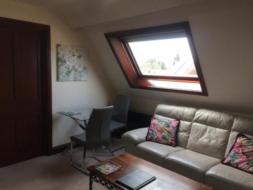 a living room with a couch and a table and a window at Stylish Apartment in Stone-Built Former Rectory in Penrith
