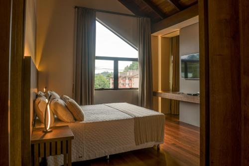 a bedroom with a bed and a large window at Hotel Pousada Kaster in Gramado