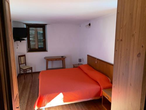 1 dormitorio con cama roja y ventana en Casa a Miazzina en Miazzina