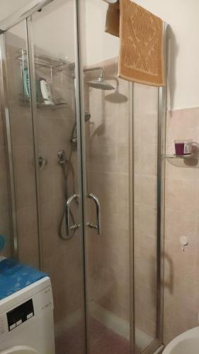 y baño con ducha y puerta de cristal. en Mini appartamento en Livorno