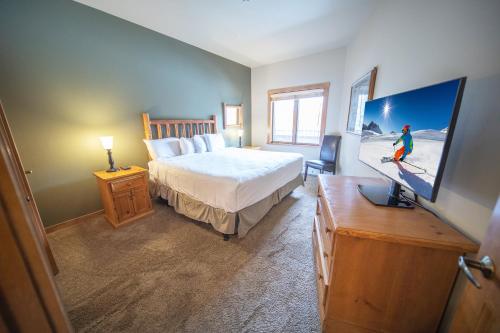 a bedroom with a bed and a tv in it at Arapahoe Lodge 8119 in Keystone