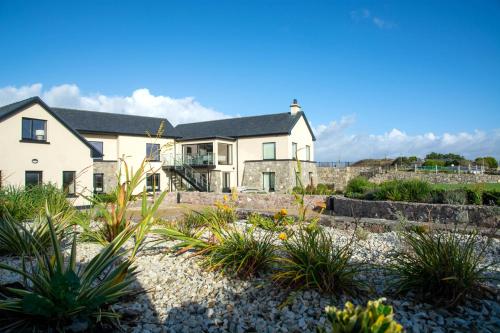 a house on the beach with plants in the foreground at Sruthan Pier House in Carraroe