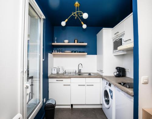 a kitchen with white cabinets and blue walls at Experience olympique proche Paris in Le Plessis-Robinson