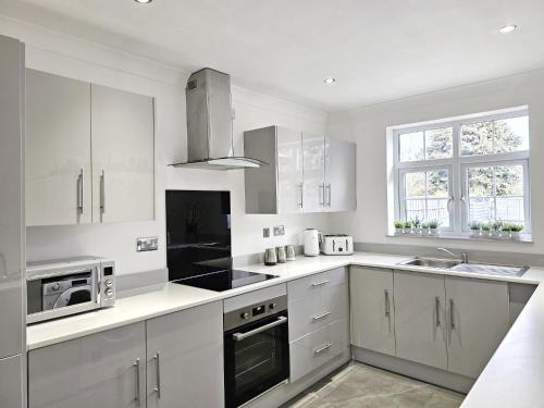 a kitchen with white cabinets and a stove top oven at Racecourse Retreat in York