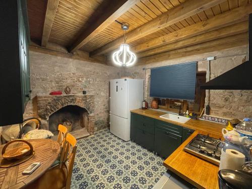 a kitchen with a refrigerator and a table and a fireplace at Keyifli Bir Taş Ev SAÇAKLIHANE Çanakkale Tavaklı in Ezine