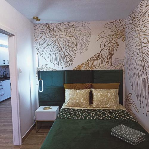 a bedroom with a green bed with a mural of palm trees at BaltikApart in Hel