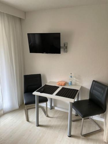 a table with two chairs and a television on a wall at Geschäfts- und Ferienwohnung 111 in Bad Urach