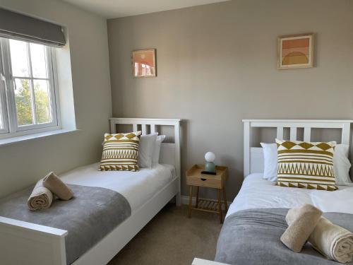 two beds in a room with two windows at Caramel Cottage at The Bay Filey, sleeps 6, 2 dogs welcome for free too in Filey