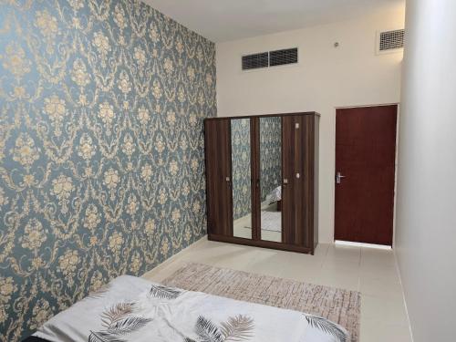 een slaapkamer met een bed en een muur met een spiegel bij Pretty Room in Shared Apartment in Ajman 