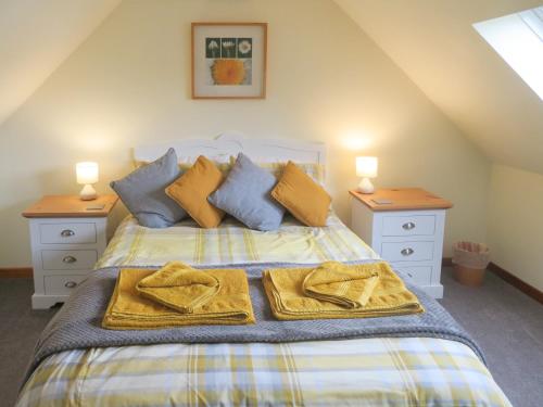 um quarto com uma cama com almofadas amarelas e azuis em Breacwell Cottage em Bonar Bridge