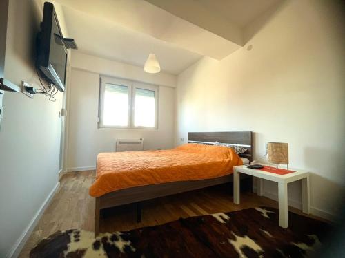 1 dormitorio con cama de color naranja y ventana en Apartman Nikol, en Kumanovo