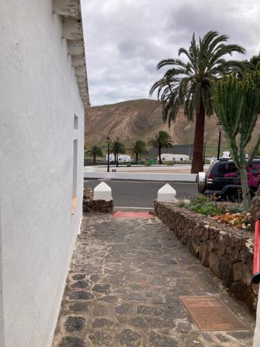 einen Steinweg neben einem Gebäude mit einer Palme in der Unterkunft Centro Ave Fénix in Femés