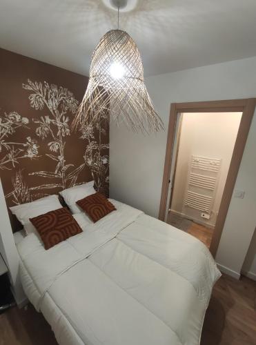 a bedroom with a large white bed with a chandelier at Calme et cosy, proche hyper centre de Nantes in Nantes