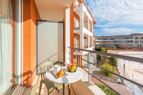 een balkon met een tafel met een kom eten erop bij Appart'City Classic Aix-en-Provence - La Duranne in Aix-en-Provence