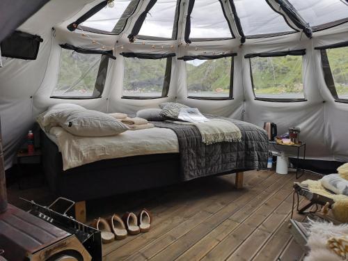 a bedroom with a bed in a tent with windows at FLO Lofoten eco glamping in Valberg