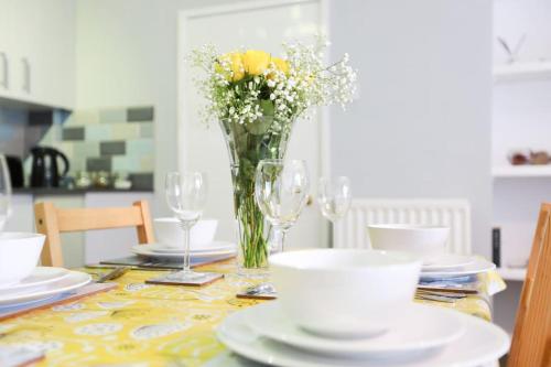 a dining room table with a vase of flowers and glasses at Woodside Ash hot tub & pool (sleeps 4-6) in Bideford