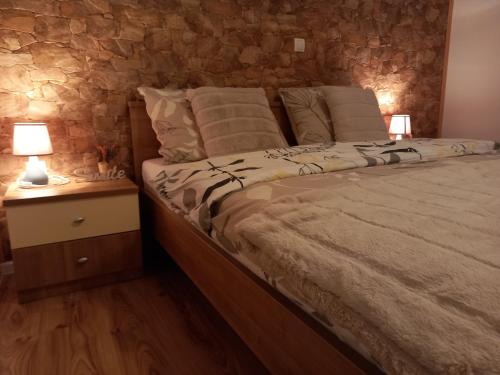 a bedroom with a bed with a stone wall at Guest House Lisina in Poljanak