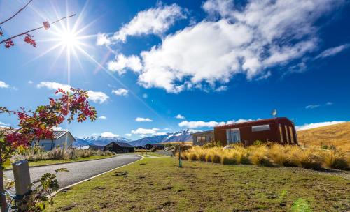 a road with a house and mountains in the background at The Red Nest - Lake Tekapo in Lake Tekapo