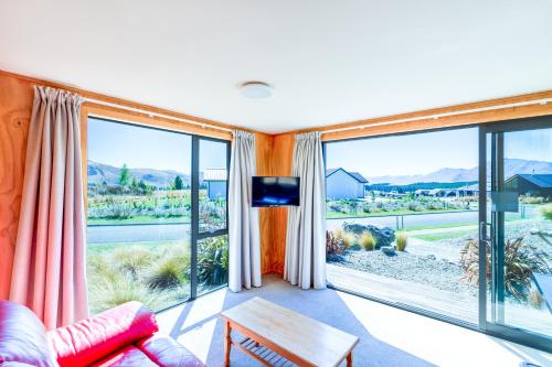 a living room with a couch and large windows at The Red Nest - Lake Tekapo in Lake Tekapo