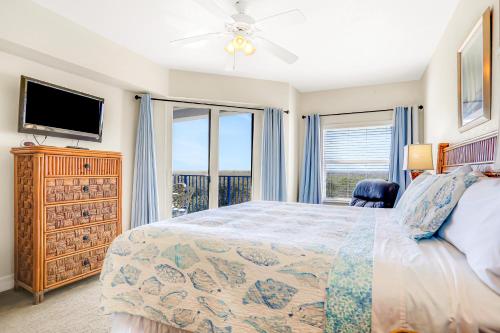 a bedroom with a bed and a tv and windows at Oceanwalk 17-406 in New Smyrna Beach